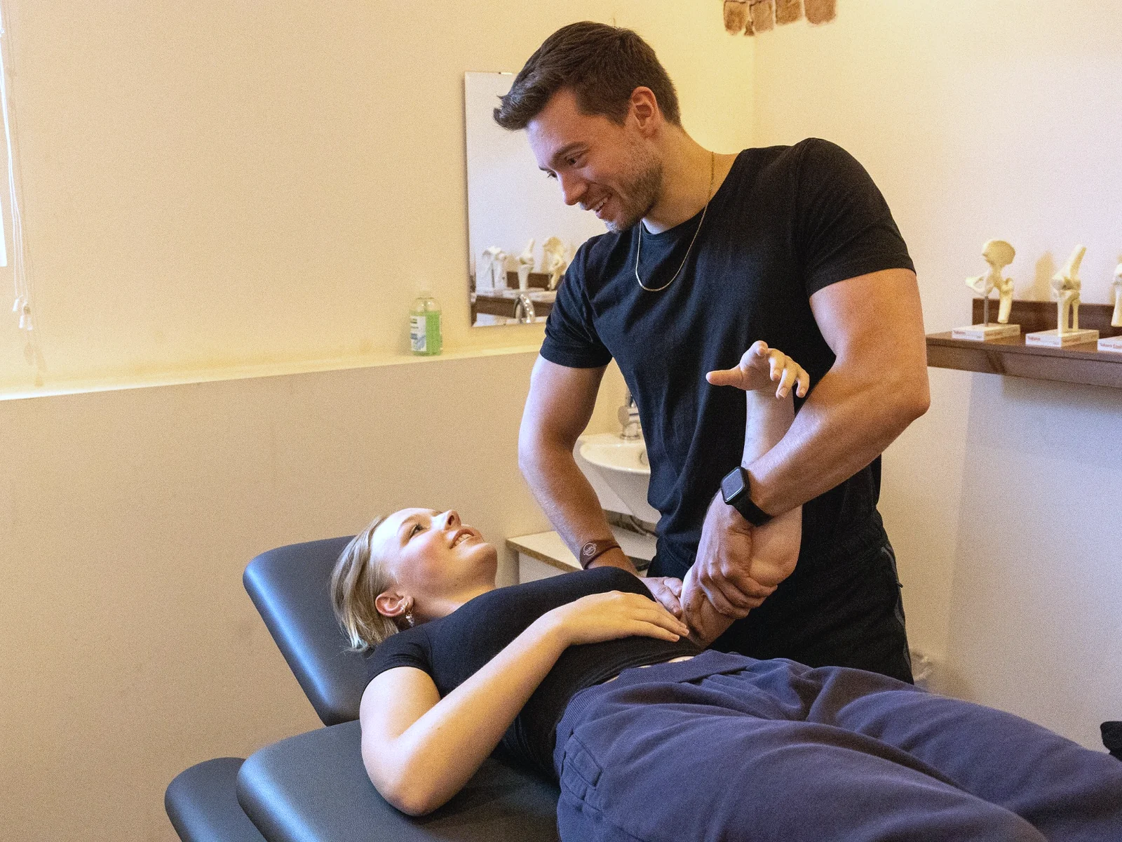 Physiotherapeut behandelt eine Patientin am Arm in einer Campus-Praxis